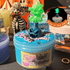 Blue Rancid Refresher slime in a jar topped with purple sprinkles and a glowing green potion bottle charm