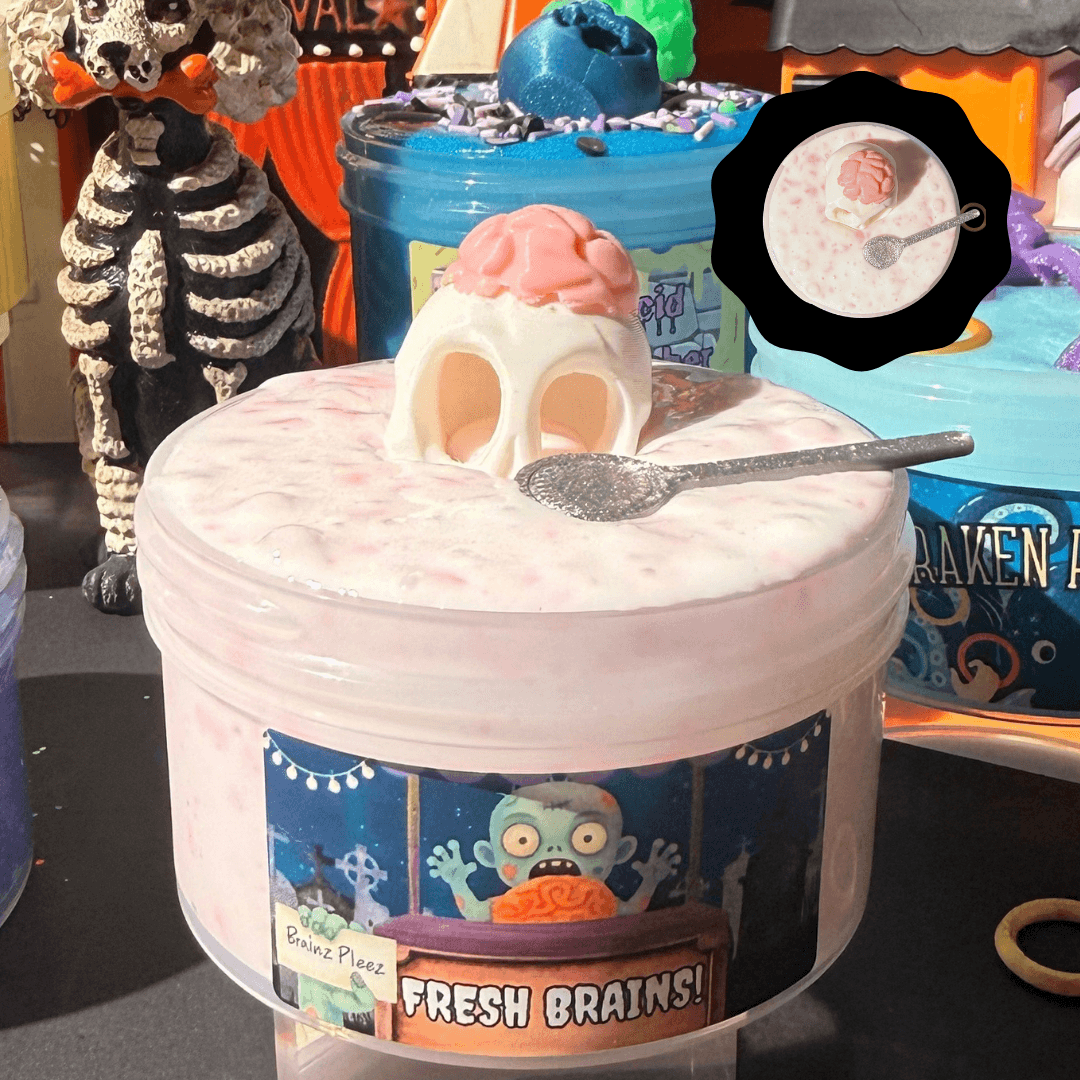White thick and glossy Fresh Brains slime in a jar with pink silica chunks, a mini silver spoon, and a 3D-printed brain charm.
