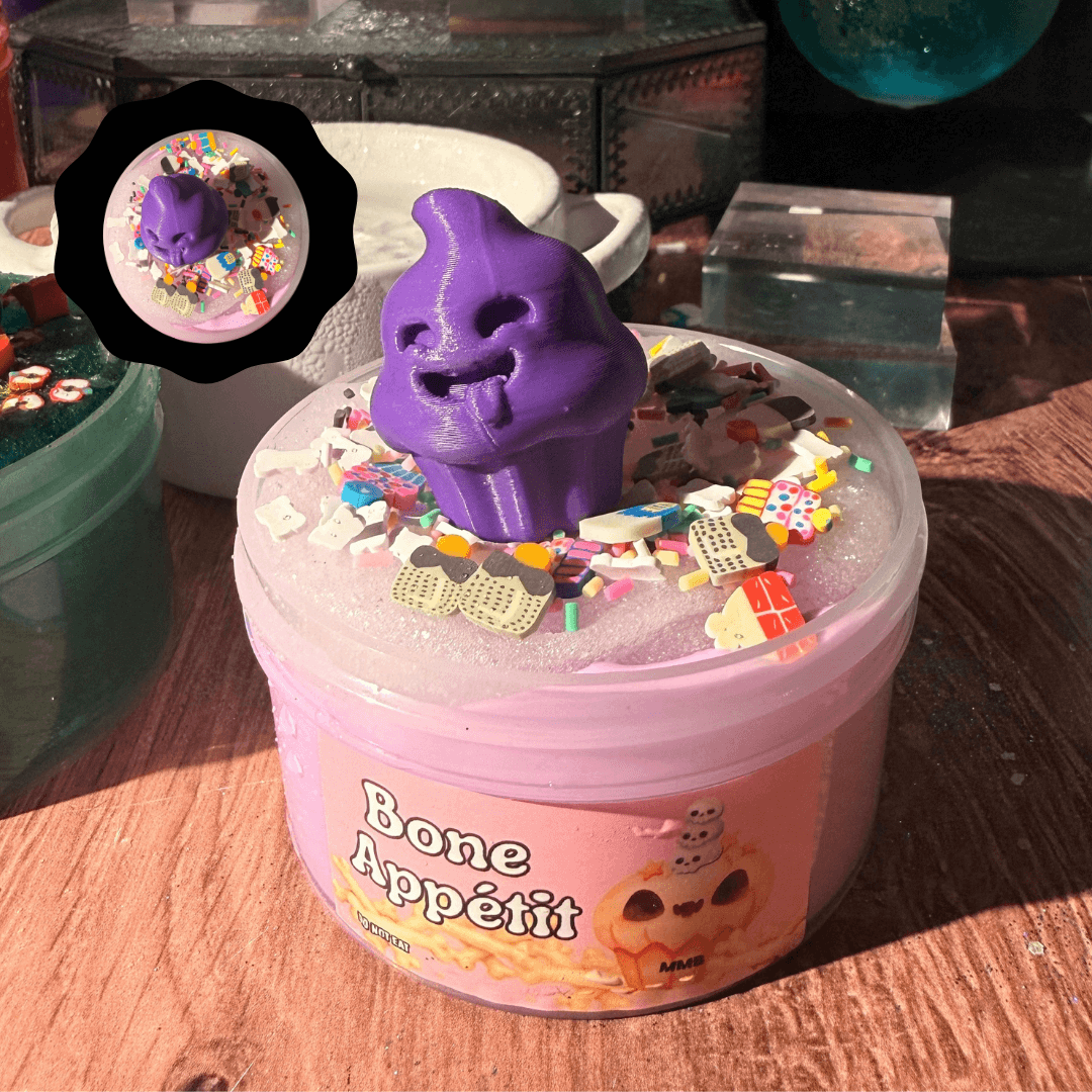 bone appétit halloween slime jar filled with pink cloud cream, topped with sparkling purple icee layer, sprinkles, and purple ghost cupcake charm