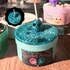 spooky sweets halloween slime jar with glittery teal wood glue base, topped with teal clear slime and blue skull lollipop figure