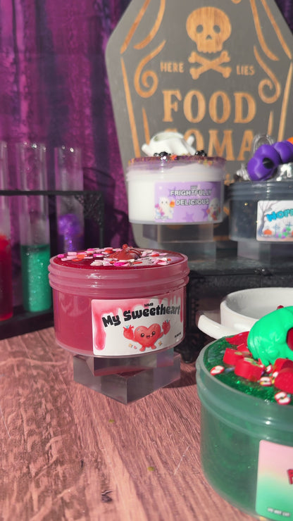 Video showing a close-up preview of Halloween-themed slimes from the Midnight Snacks collection, featuring My Sweetheart, Frightfully Delicious, and Worm Food with a graveyard tombstone background.