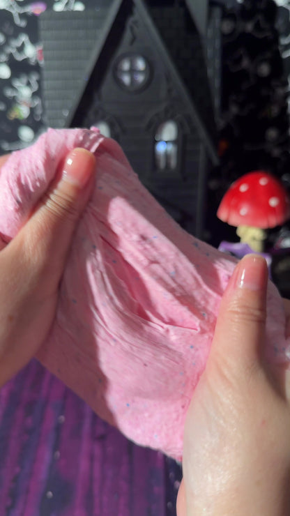 hands stretching pink cloud cream slime filled with fine snow fizz in a texture demo video