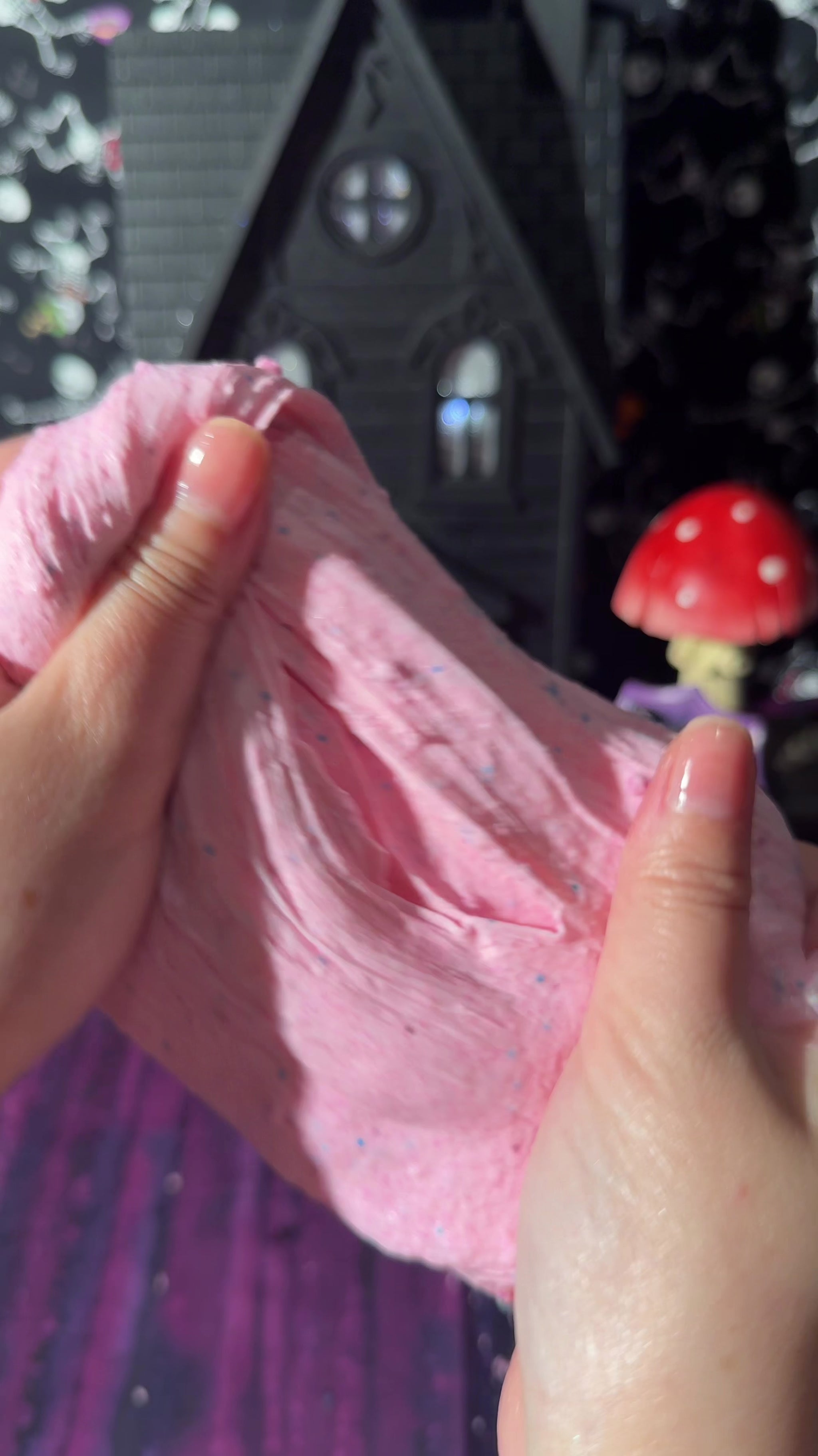 hands stretching pink cloud cream slime filled with fine snow fizz in a texture demo video