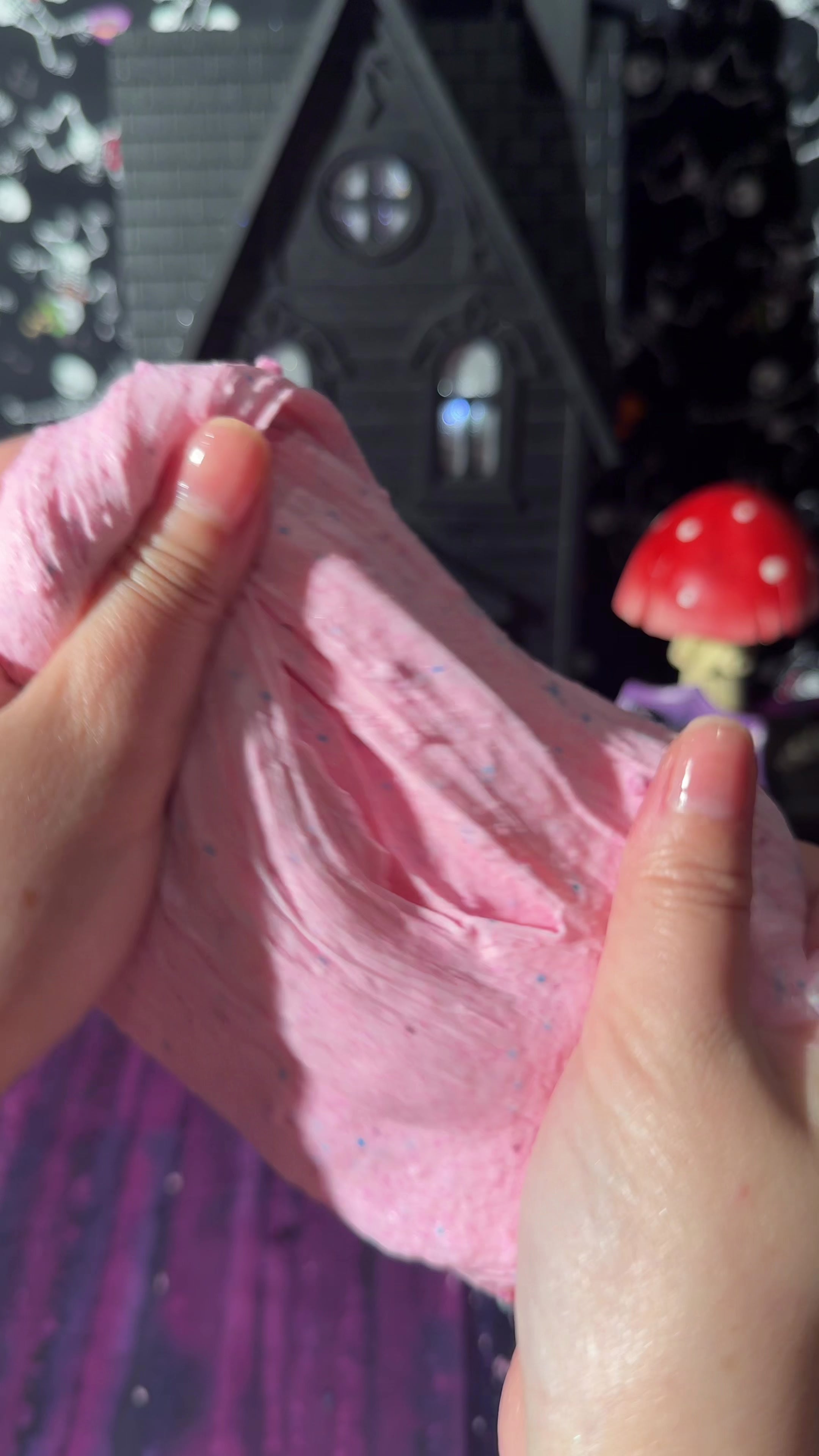 hands stretching pink cloud cream slime filled with fine snow fizz in a texture demo video